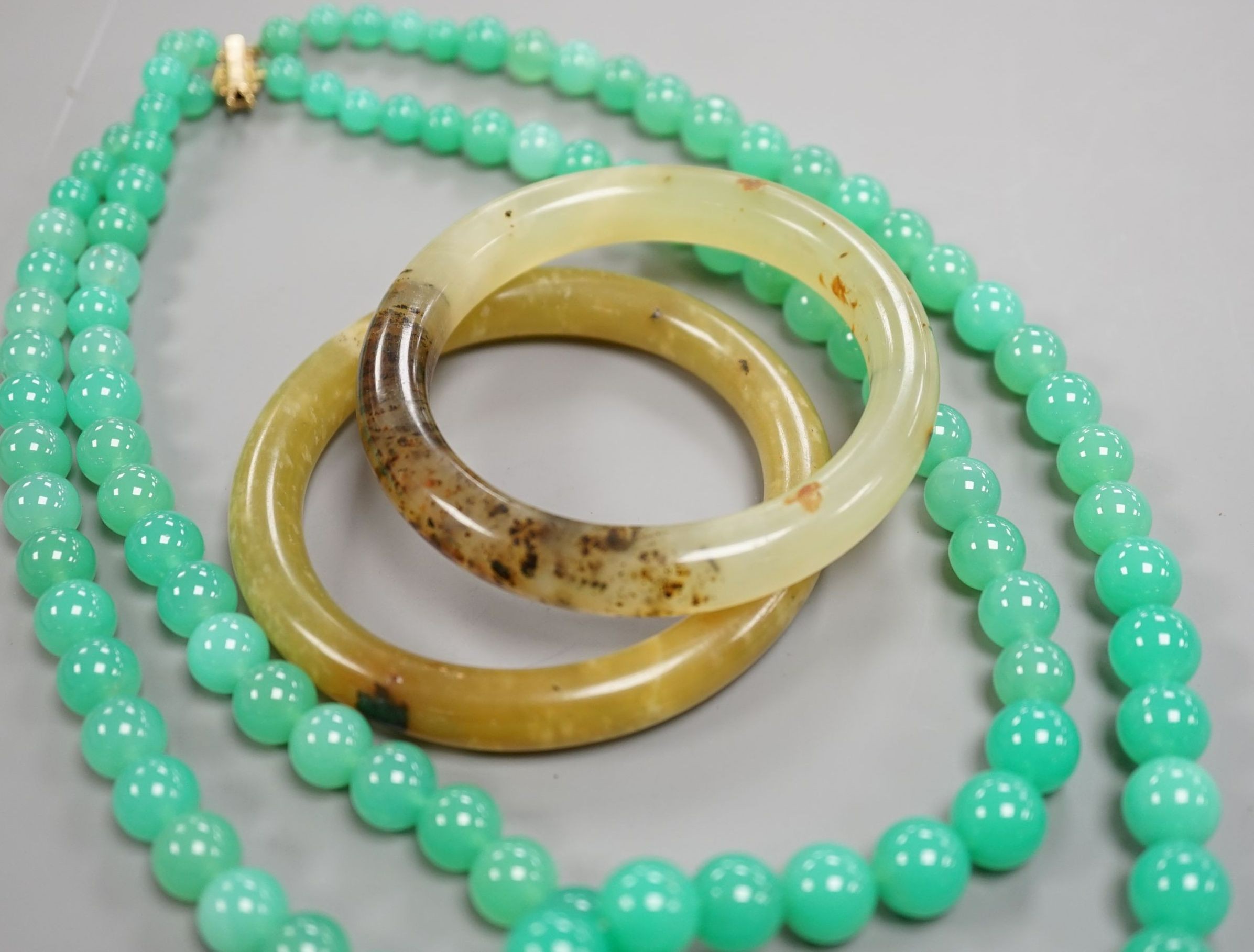 A double strand chrysoprase bead necklace with 750 yellow metal clasp, 50cm and two bowenite bangles.